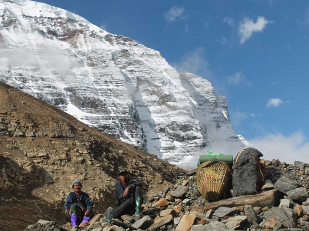 धौलागिरि हिमालको आधार शिविर जाने पर्यटकको सामान बिसाएर हिमालको फेदीमा आराम गर्दै भरिया । तस्बिरः कमल खत्री
